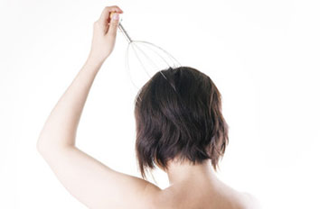 器具で頭皮マッサージをする女性